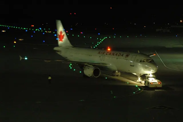 Air Canada A320 C-FTJP on an airport apron at night, illuminated by ground lights.