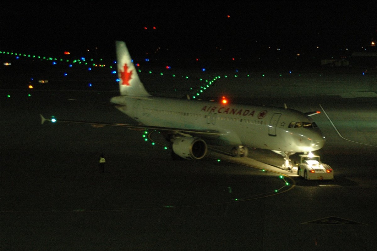 Air Canada A320 C-FTJP on an airport apron at night, illuminated by ground lights.