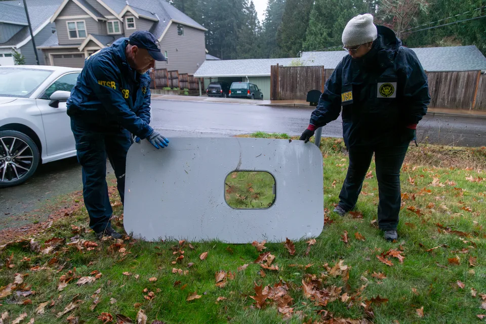 NTSB investigators holding the recovered Alaska 1282 door plug