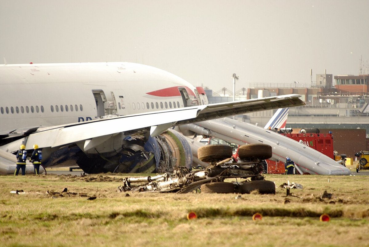 British Airways 777 on grass at Heathrow after Flight 38, with an evacuation slide deployed and debris nearby.