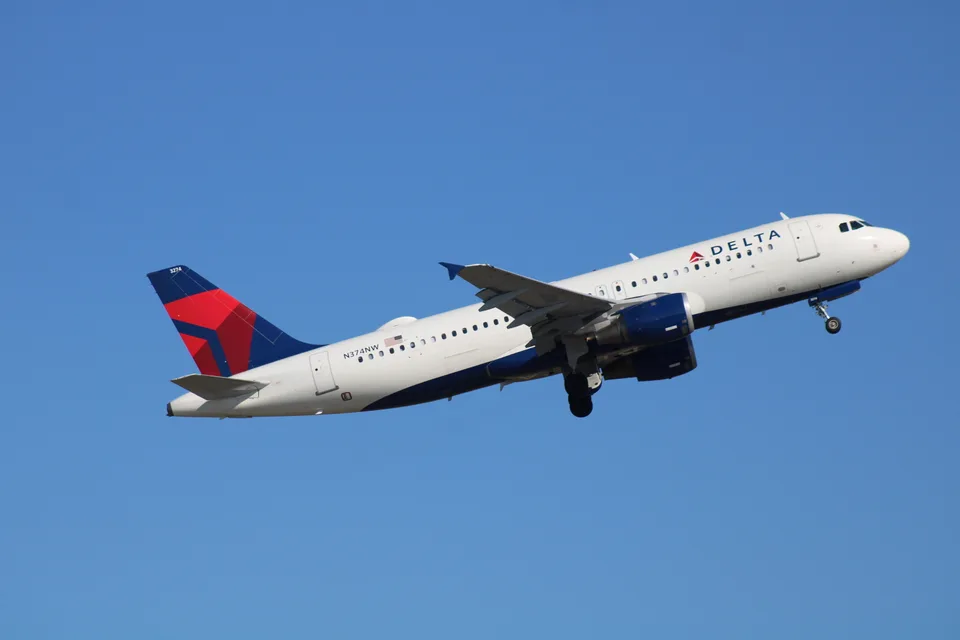 Airbus A320 N374NW climbing with its landing gear extended, wearing Delta Air Lines colours.
