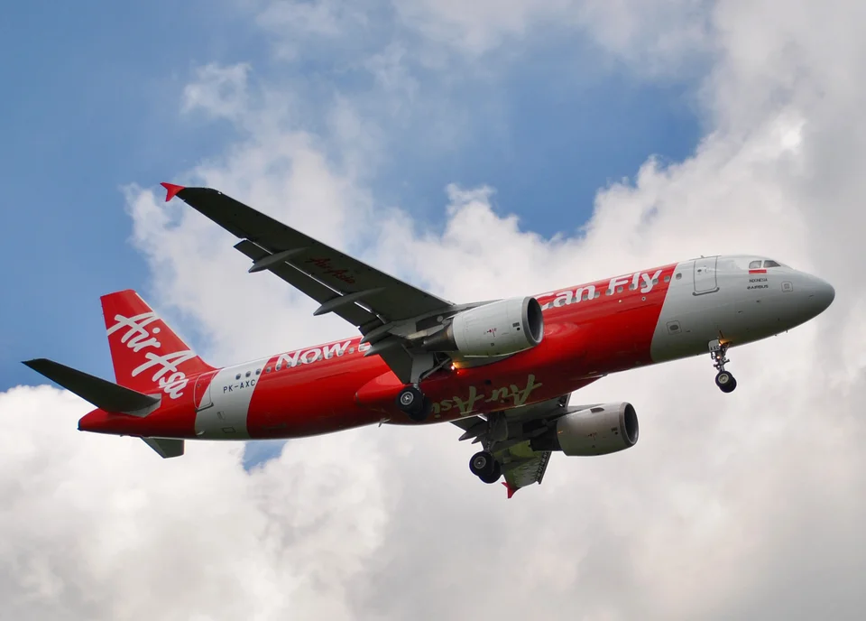 Indonesia AirAsia Airbus A320 PK-AXC with landing gear extended above Bali.